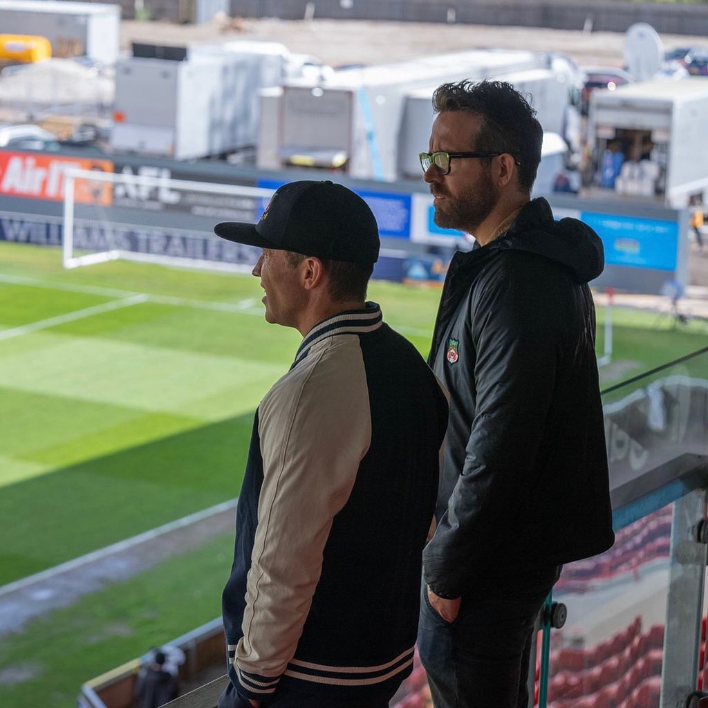 Ryan Reynolds and Rob McElhenney looking at a football pitch