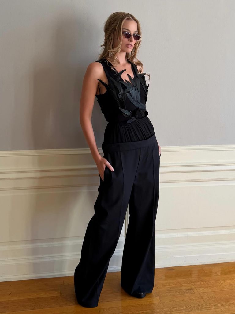 Margot robbie posed in black feathered bodysuit