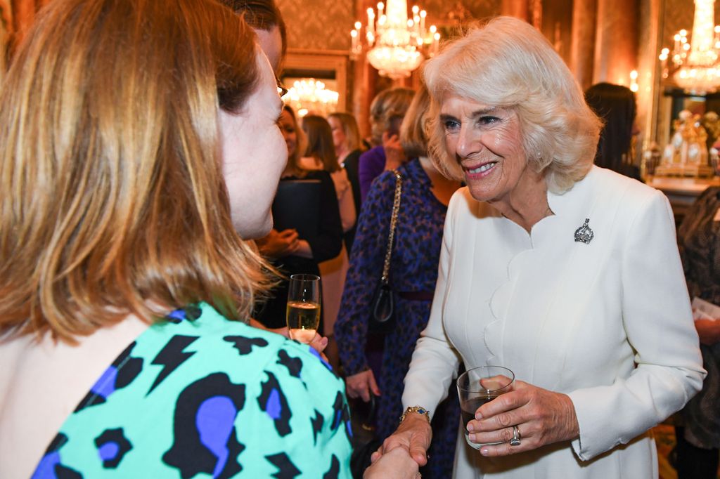 Queen Camilla in white dress meeting people