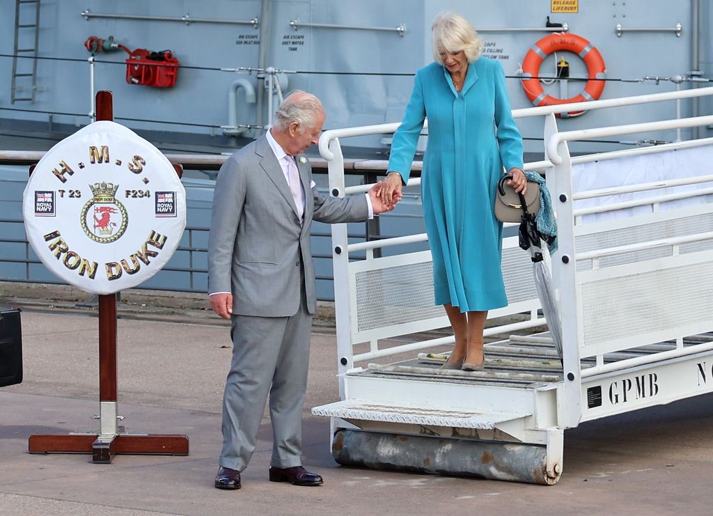King Charles III helps Queen Camilla disembark after a reception on the flight deck of Royal Navy type 23 frigate, HMS Iron Duk