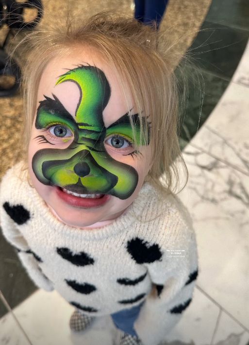 A young girl with the Grinch painted on her face