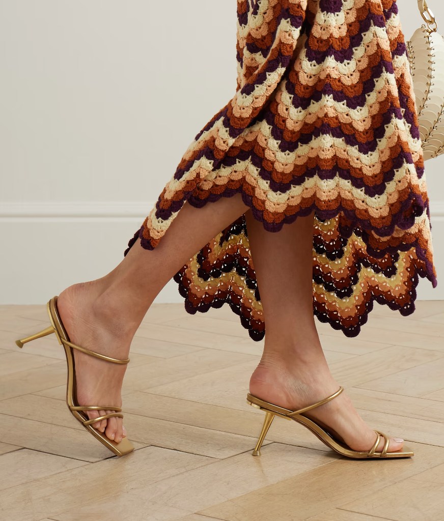 A model poses in a pair of gold heels and a crochet colourful skirt