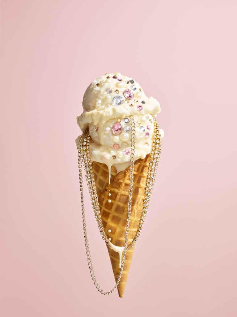 A vanilla icecream cone with chains and crystals on it