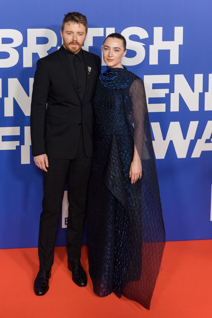 smiling couple posing on red carpet