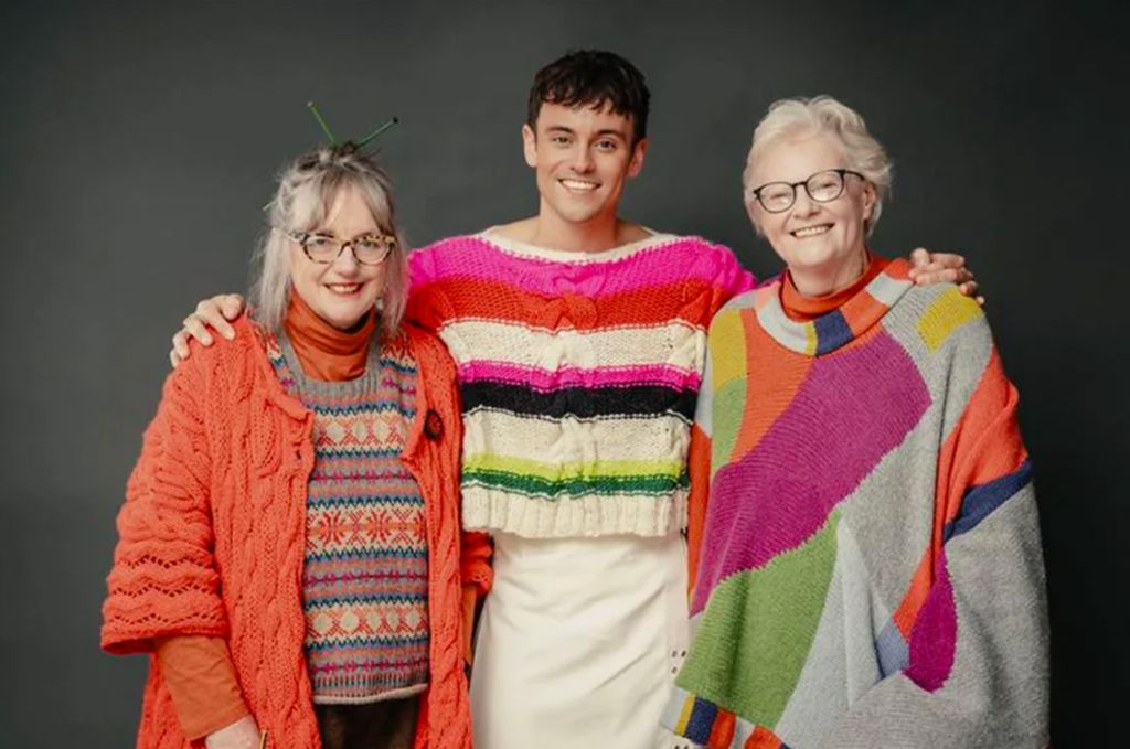 Tom Daley in a knitted jumper with his arms around Di Gilpin and Sheila Greenwell