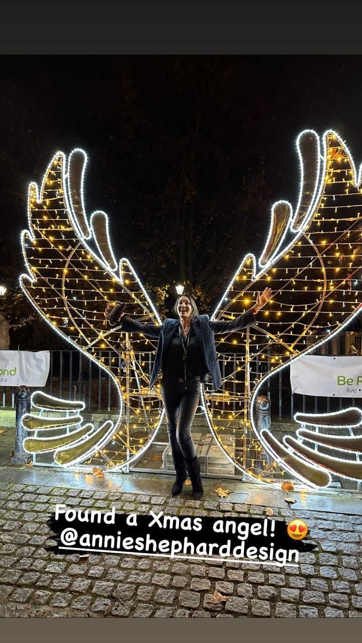 annie shephard posing against angel wing light display 