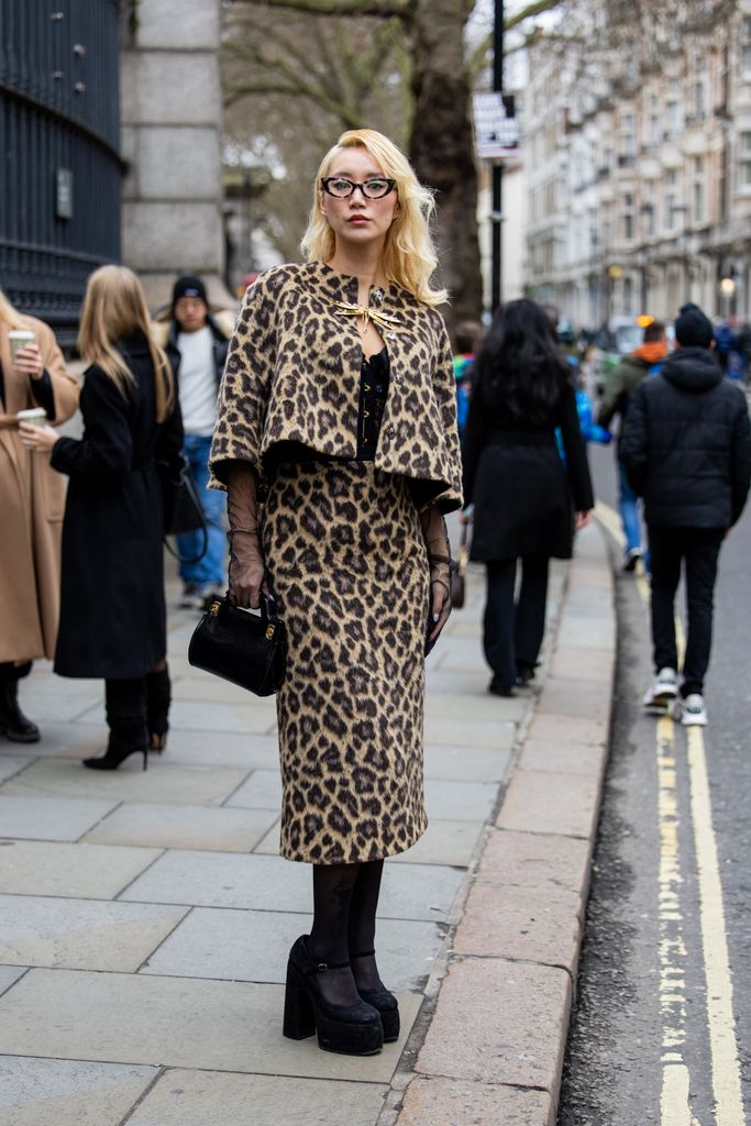 Betty Bachz delivered a masterclass in 'Mob Wife' glamour in her cropped leopard cape, matching skirt, and jet black accessories outside Erdem. 