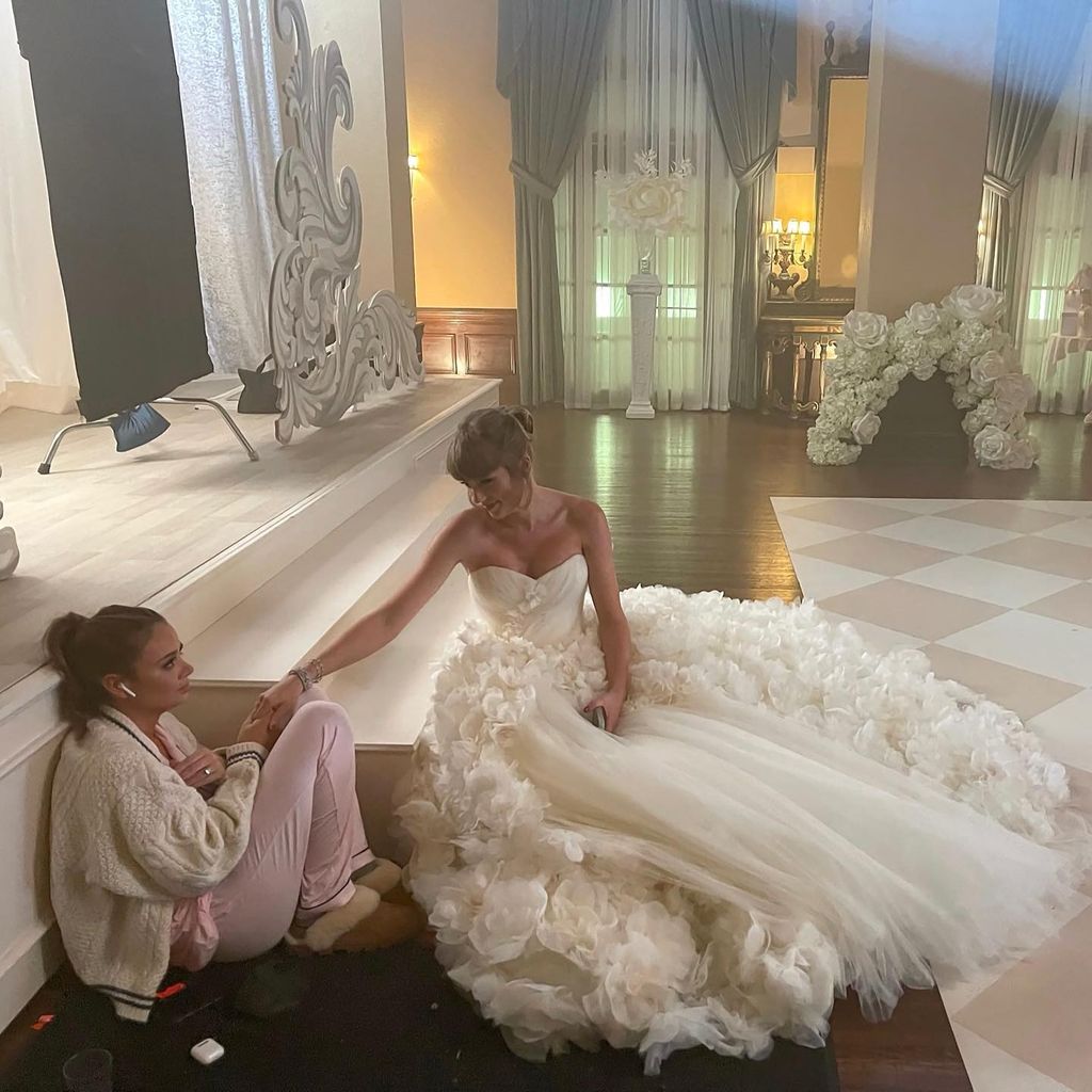 Taylor Swift sitting on the ground in a wedding dress