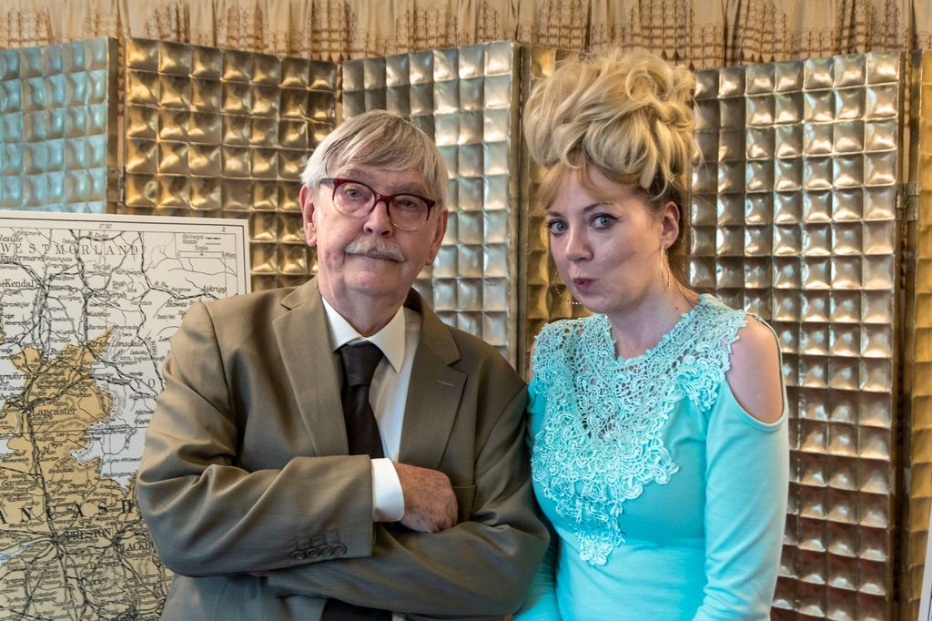 older man in glasses next to woman in blue top and blonde hair