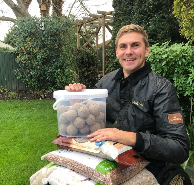 man with bird feeding bucket and packets in garden