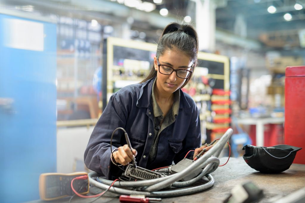 Female apprentice electrician in car factory