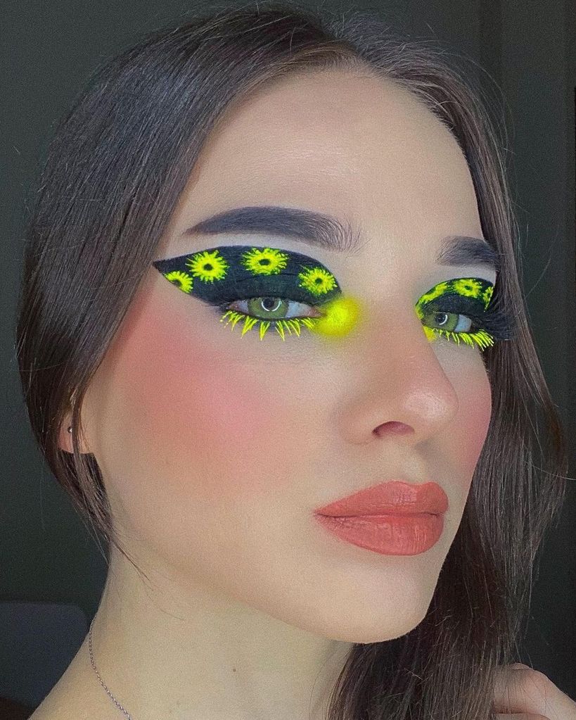 Woman with thick black eyeliner and neon flower accents 