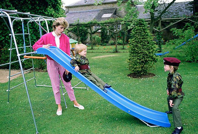Princess Diana watches as Harry and William play on a slide in 1986
