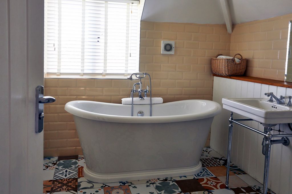 roll top bath in a yellow bathroom with patterned tiles