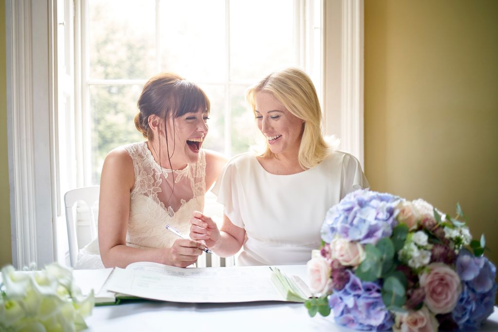 brides laughing signing marriage register