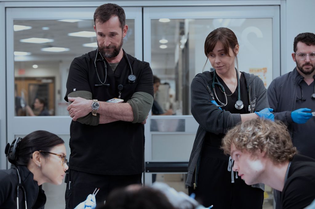 Noah Wyle and Fiona Dourif as Dr Robby and Dr McKay watch two med students in a still from The Pitt  (Warrick Page/HBOMAX)