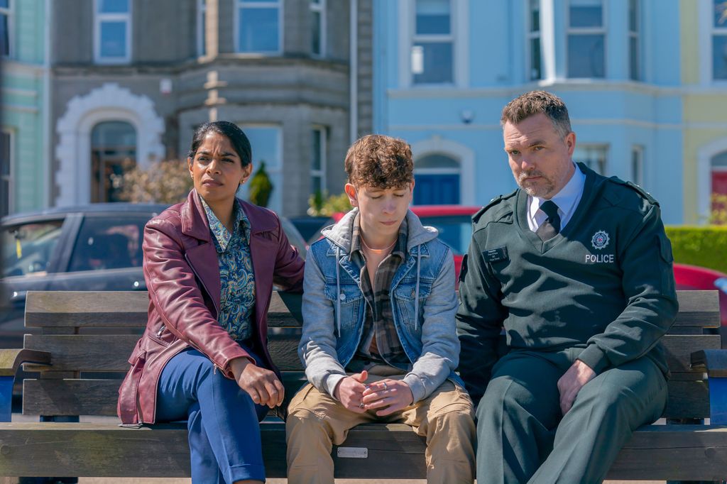 police officer, woman and young man sitting on bench