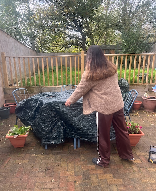 woman covering outdoor table with plastic