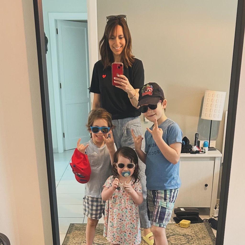 mother taking mirror selfie with three children 