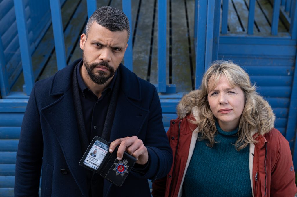 man with police badge next to woman in red coat