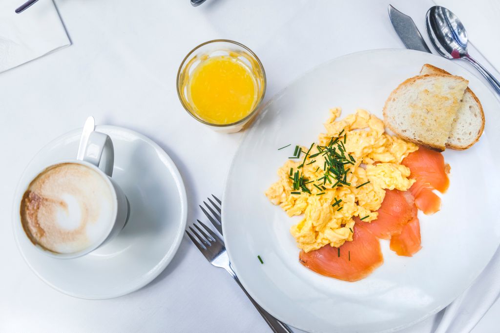 Brunch flat lay with cappuccino, orange juice, smoked salmon, eggs and bread over bar table. Innsbruck, Tyrol, Austria.
