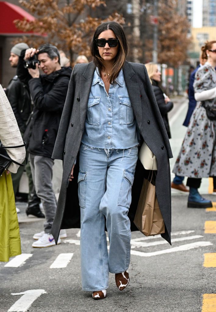 A guest is seen wearing a gray coat, denim top and pants with cream bag outside the Jason Wu show during NYFW