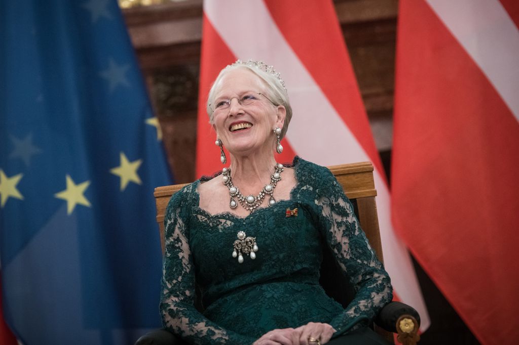Queen Margrethe wearing a green lace gown in front of flags during Germany state visit 2021