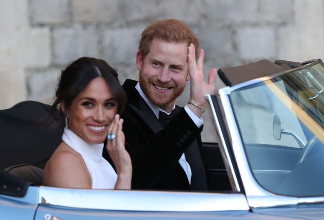 Duchess Meghan Markle and Prince Harry smile as they drive away at their wedding reception
