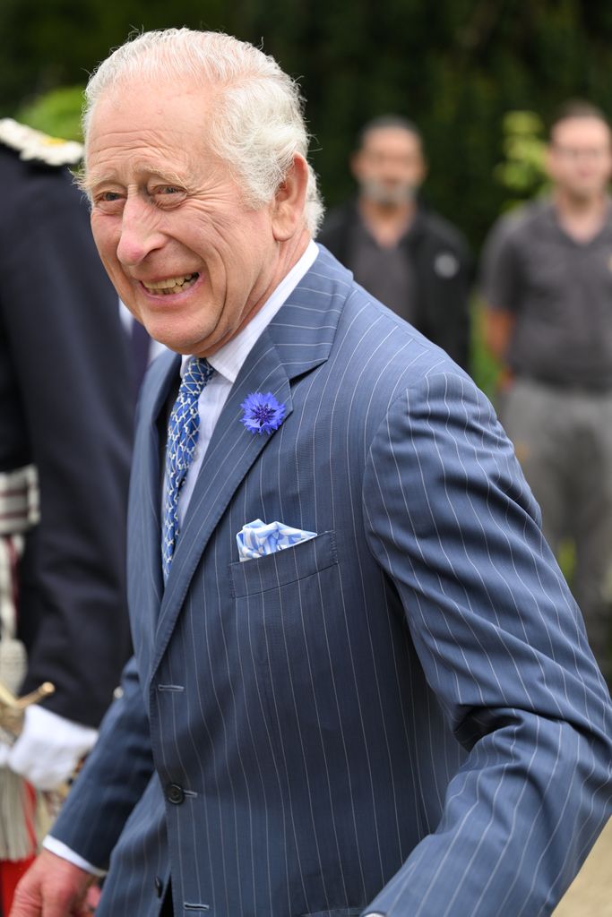 King Charles smiling in a blue suit
