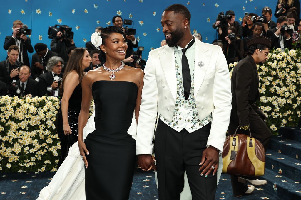 Gabrielle Union and Dwyane Wade looking fondly at eachother, holding hands on the red carpet at the Met Gala