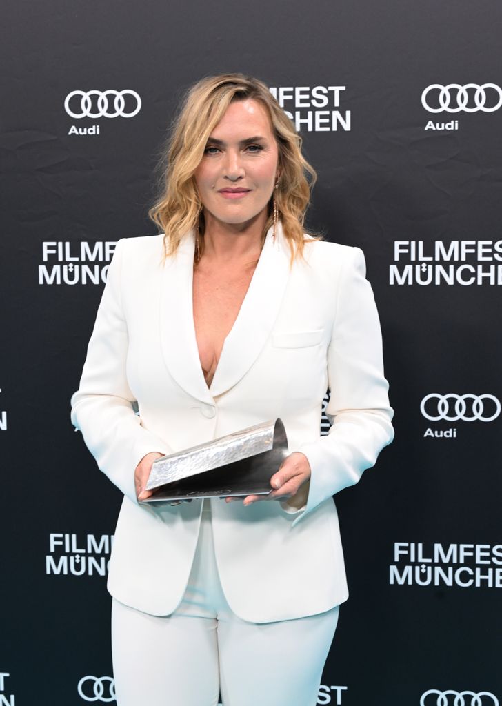 Kate Winslet holding award in white suit