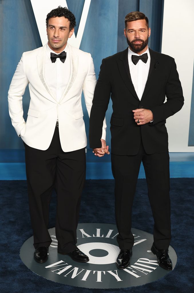 Jwan Yosef in a white suit holding hands with Ricky Martin in a black suit