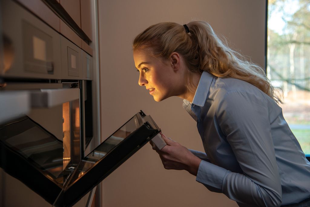 Young Woman walks to the oven to check 