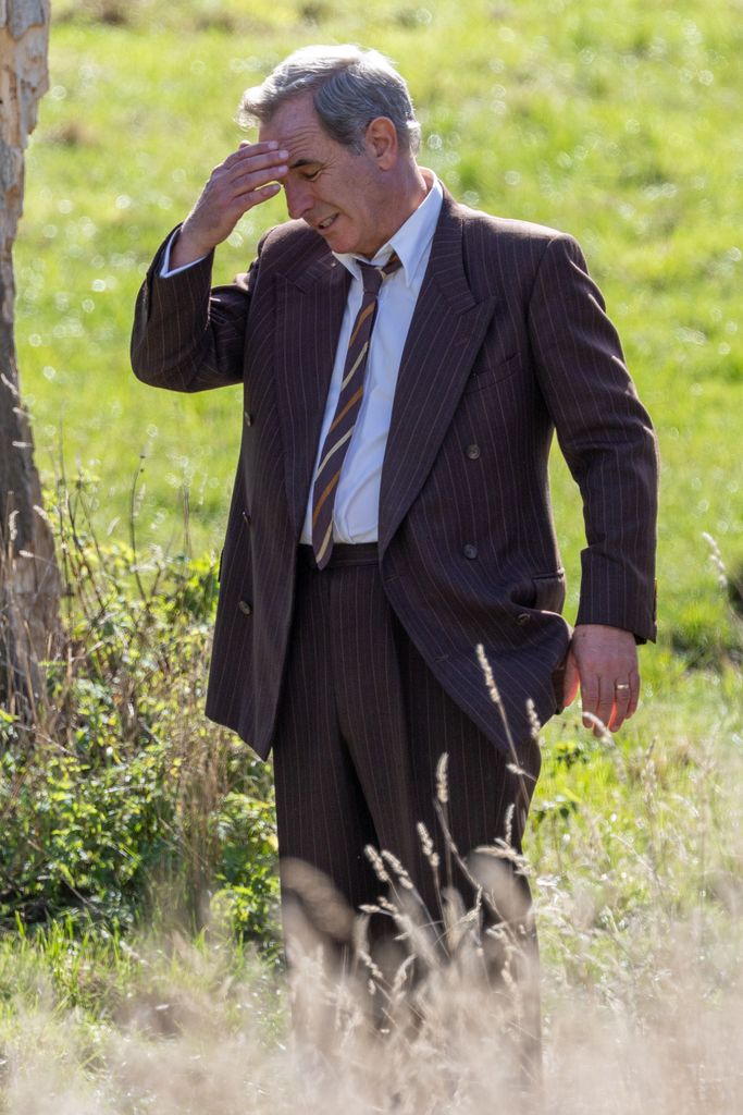 man standing in meadow wearing suit