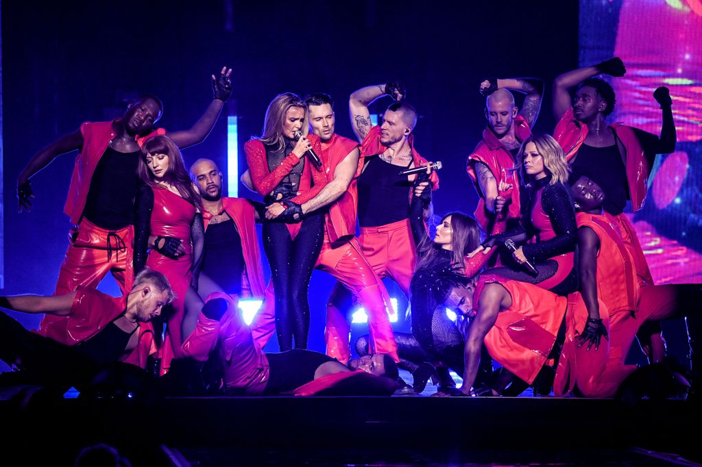 Girls Aloud on stage with dancers in red costumes