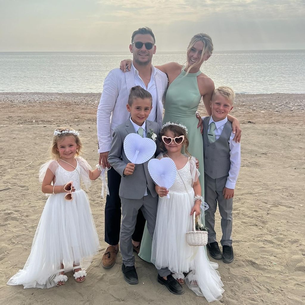 Danny with wife and kids on beach in wedding outfits