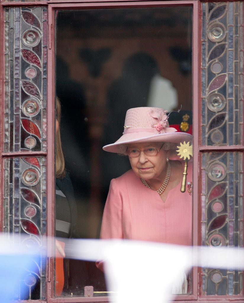 Queen Elizabeth II peers out of a window of Manchester Town Hall to view a Jubilee Garden where the wedding took place