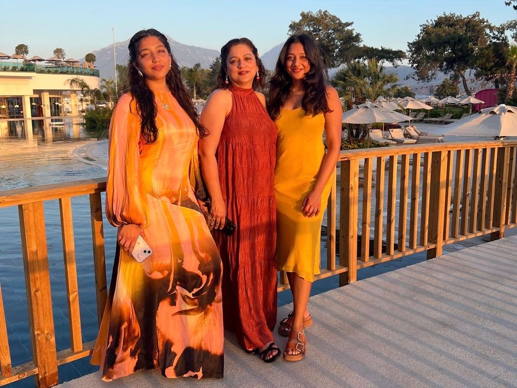 Three women in summer clothes posing in front of a pool