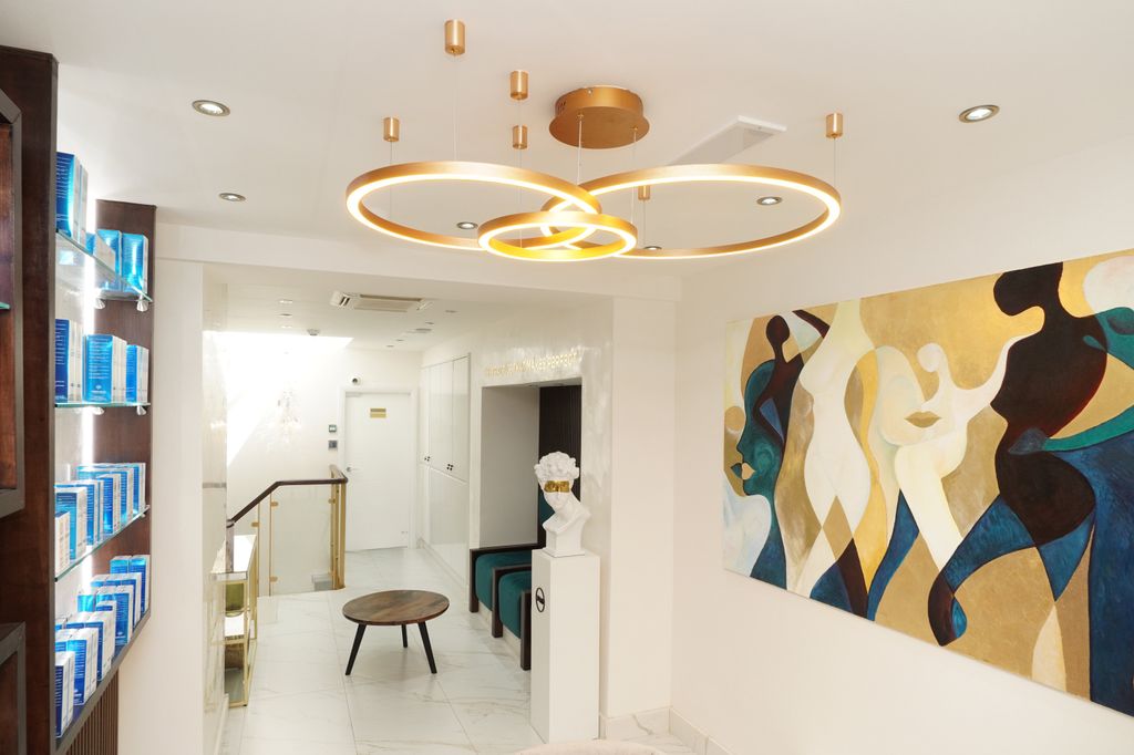 Elegant interior of DrMediSpa, featuring modern gold chandeliers, blue product displays, abstract art in gold and blue, and a sleek reception area with a white bust sculpture.