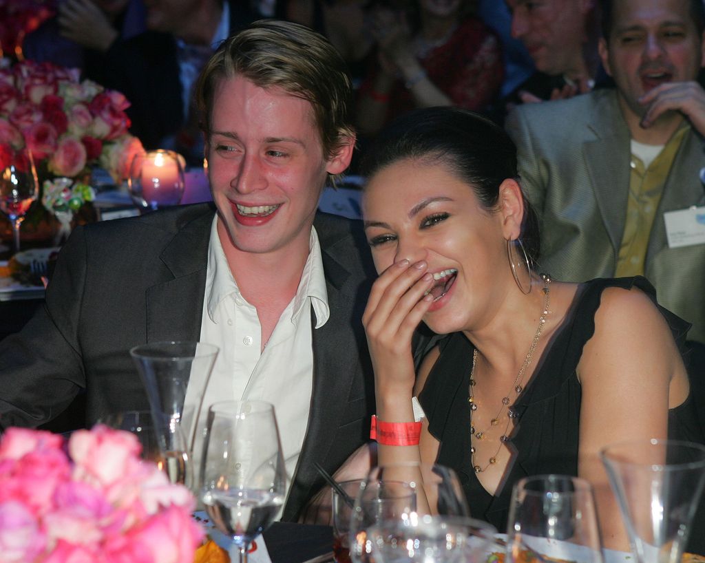 Macaulay Culkin and girlfriend Mila Kunis sat together laughing 