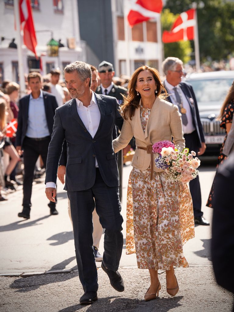 King Frederik and Queen Mary walk through Grasten with arms around each other