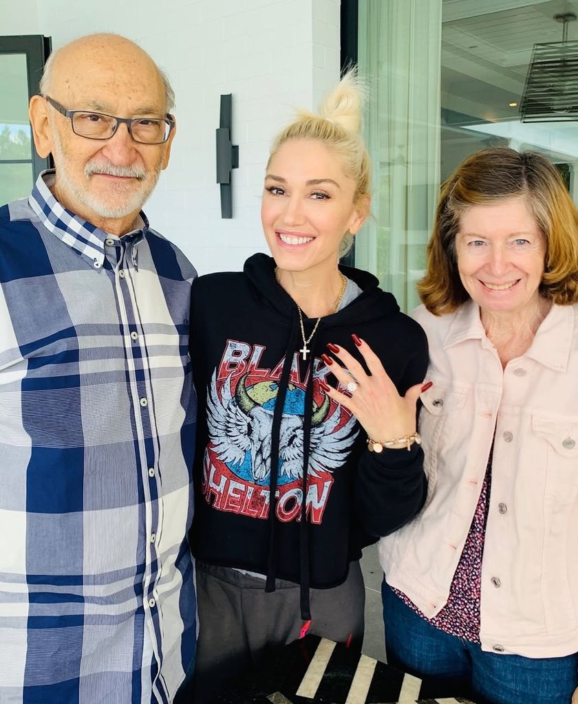Gwen showing her engagement ring while posing with parents