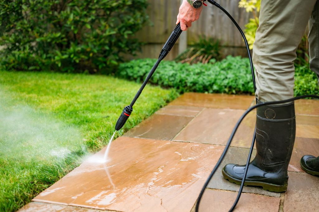 man pressure washing a patio
