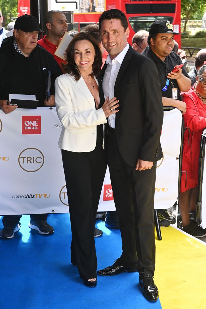 Shirley Ballas in a black jumpsuit and white jacket with Danny Taylor at The TRIC Awards 2022