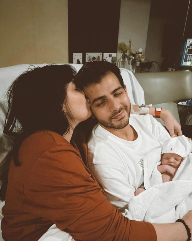 Daisy Lowe and Jordan Saul on hospital bed holding a baby