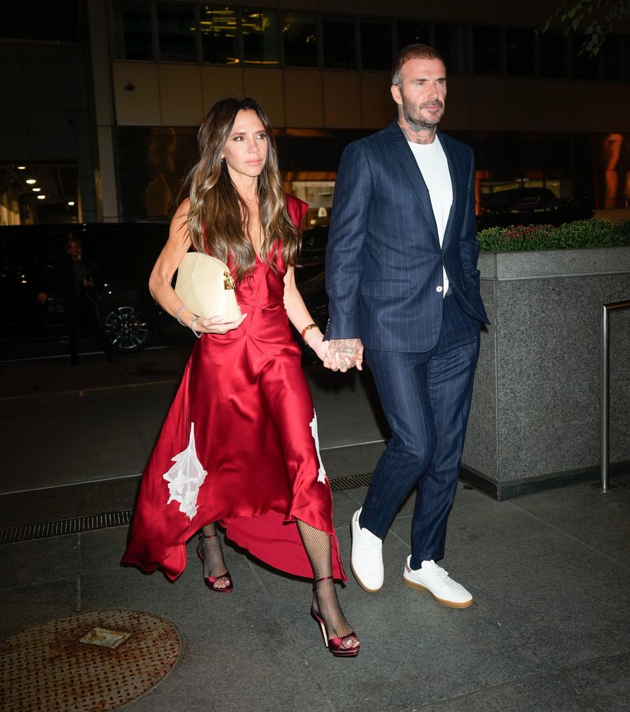 Victoria and David Beckham hand in hand in smart clothing 