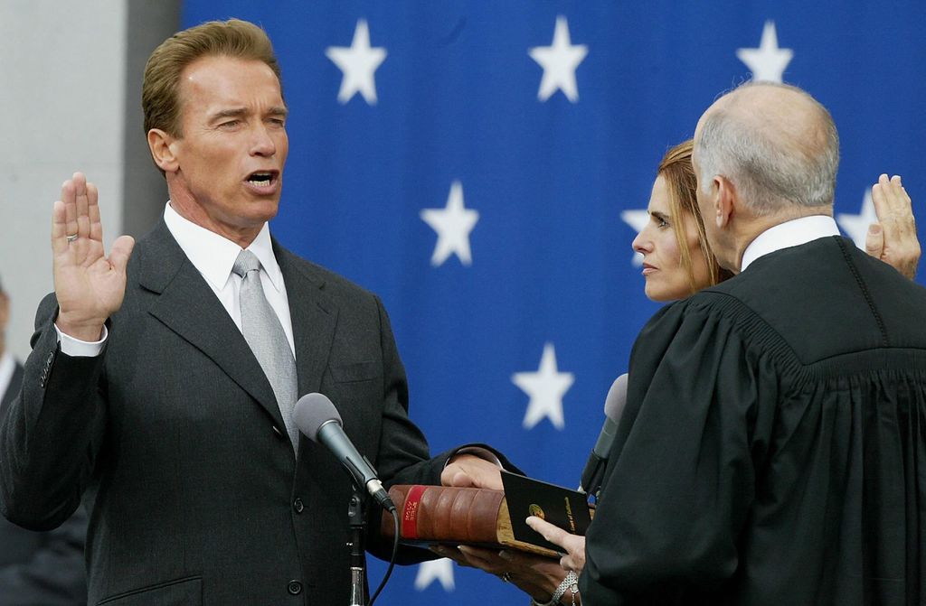 Arnold Schwarzenegger takes the oath of office administered by California Chief Justice Ronald George (R) while his wife Maria Shriver holds the bible at his inauguration as governor of the state of California, 17 November 2003