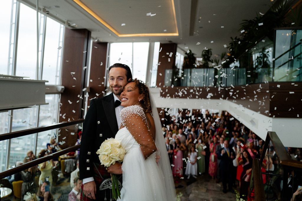 Mel B smiling and hugging her husband Rory while confetti is thrown over them
