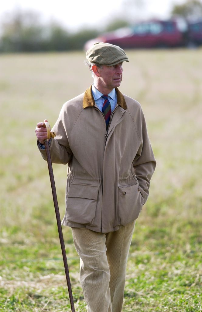 King Charles in a tweed cap walking with a stick