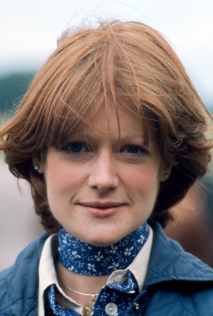 Lady Sarah looking at the camera in a close-up shot wearing a blue jacket 